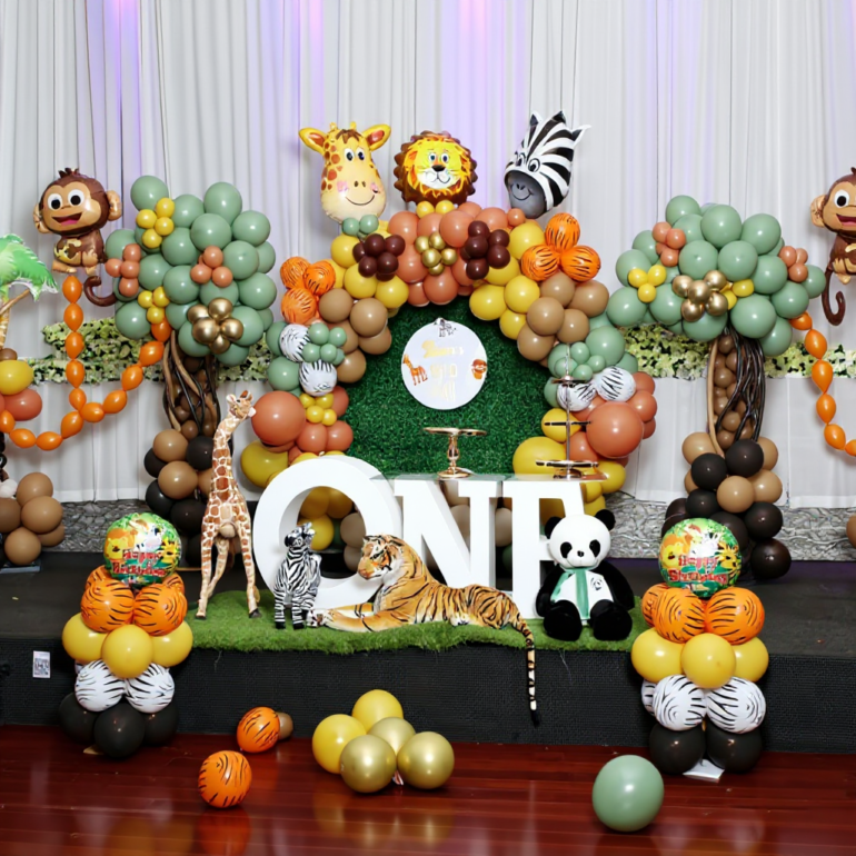 Jungle safari theme kids birthday decoration in Melbourne with sage green, white and gold balloon garland, safari animal props and custom name backdrop by JK Deco.