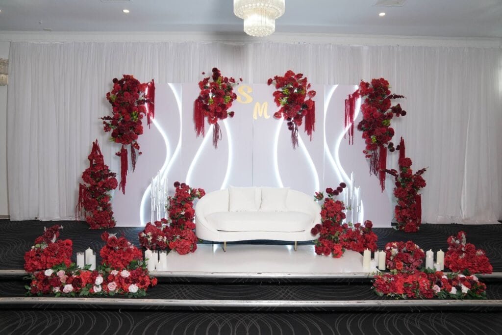 Elegant bridal stage decor with red floral arrangements in Melbourne.
